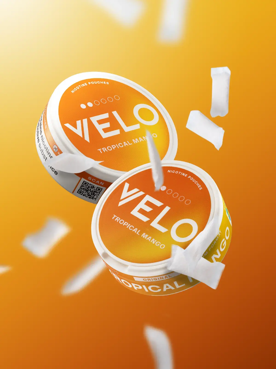 Two cans of Tropical Mango Velo nic pouches floating on an orange background